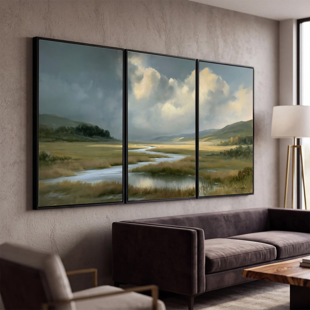 A winding stream through an open meadow beneath large sunlit clouds 3 piece framed canvas wall art displayed in a modern living room
