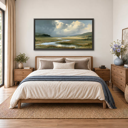 A winding stream through an open meadow beneath large sunlit clouds single framed canvas wall art styled in an interior