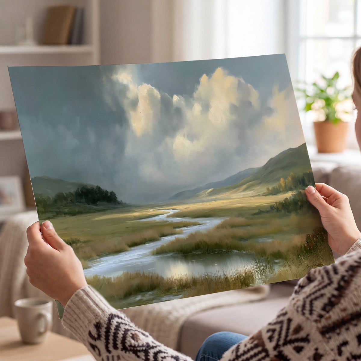 A winding stream through an open meadow beneath large sunlit clouds single poster print held in hands