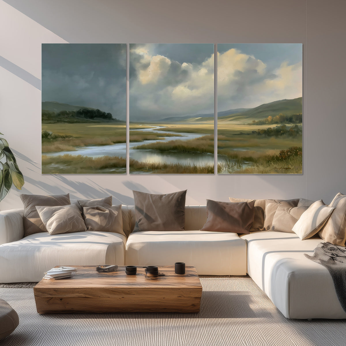 A winding stream through an open meadow beneath large sunlit clouds set of 3 poster prints displayed in a living room