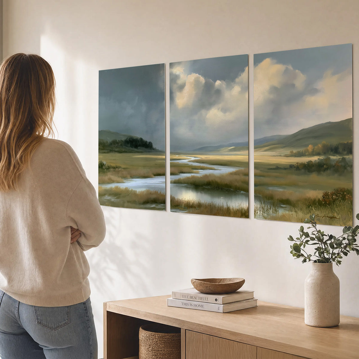 A winding stream through an open meadow beneath large sunlit clouds set of 3 poster prints three panel arrangement on a wall