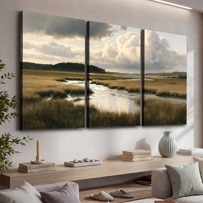 Pools of still water reflecting a dramatic cloud-filled sky across a golden marsh 3 piece canvas wall art displayed in a console