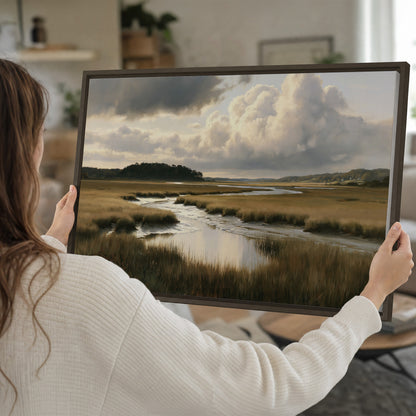 Pools of still water reflecting a dramatic cloud-filled sky across a golden marsh single framed canvas wall art held in hands