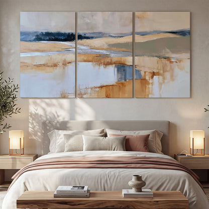 Soft horizontal bands of blue, ochre and ivory suggesting a reflected marsh landscape 3 piece canvas wall art displayed in a bedroom