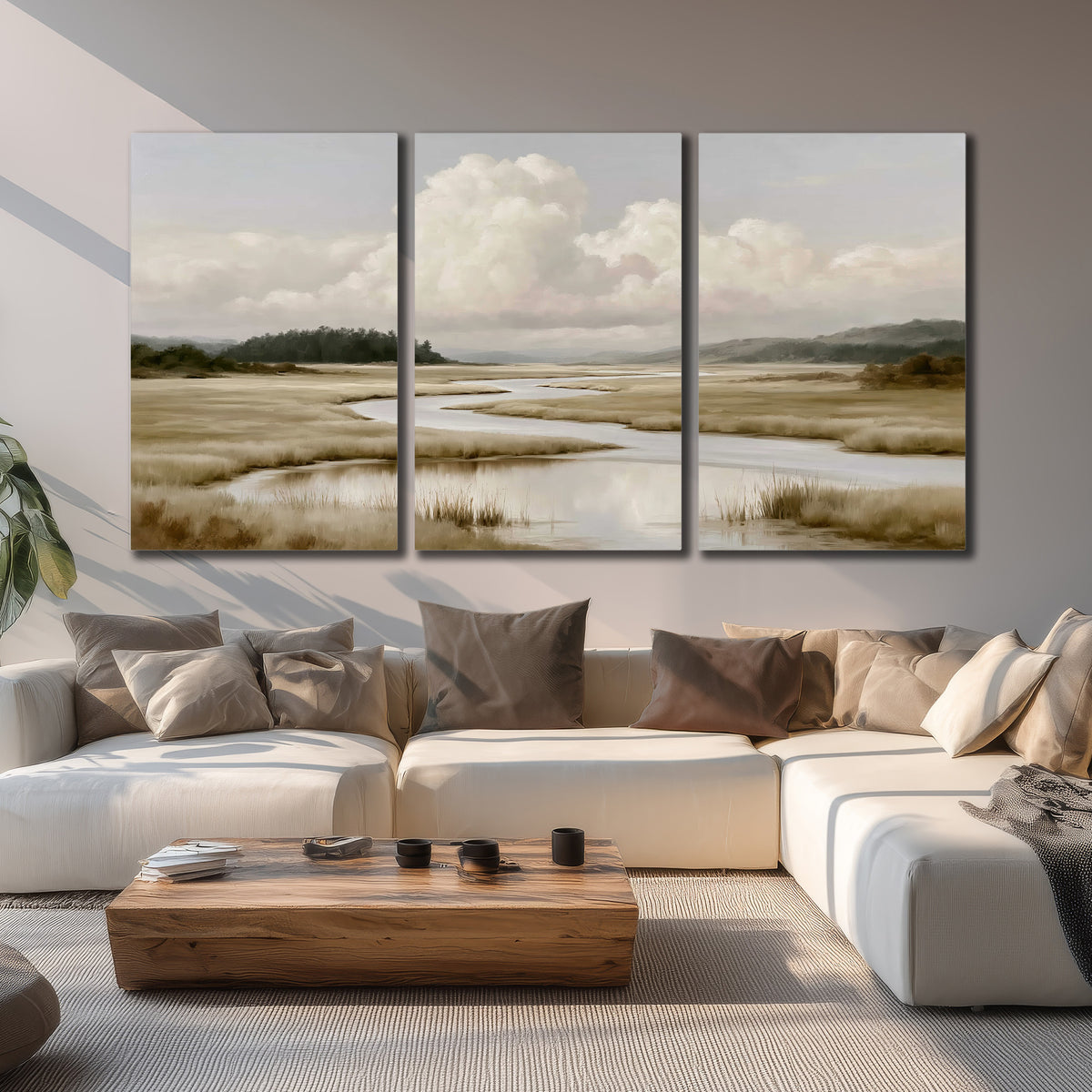 A pale winding waterway crossing quiet wetlands beneath billowing white clouds 3 piece canvas wall art displayed in a living room