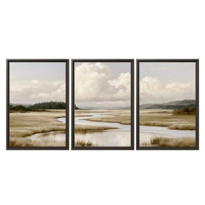 A pale winding waterway crossing quiet wetlands beneath billowing white clouds 3 piece framed canvas wall art viewed straight on
