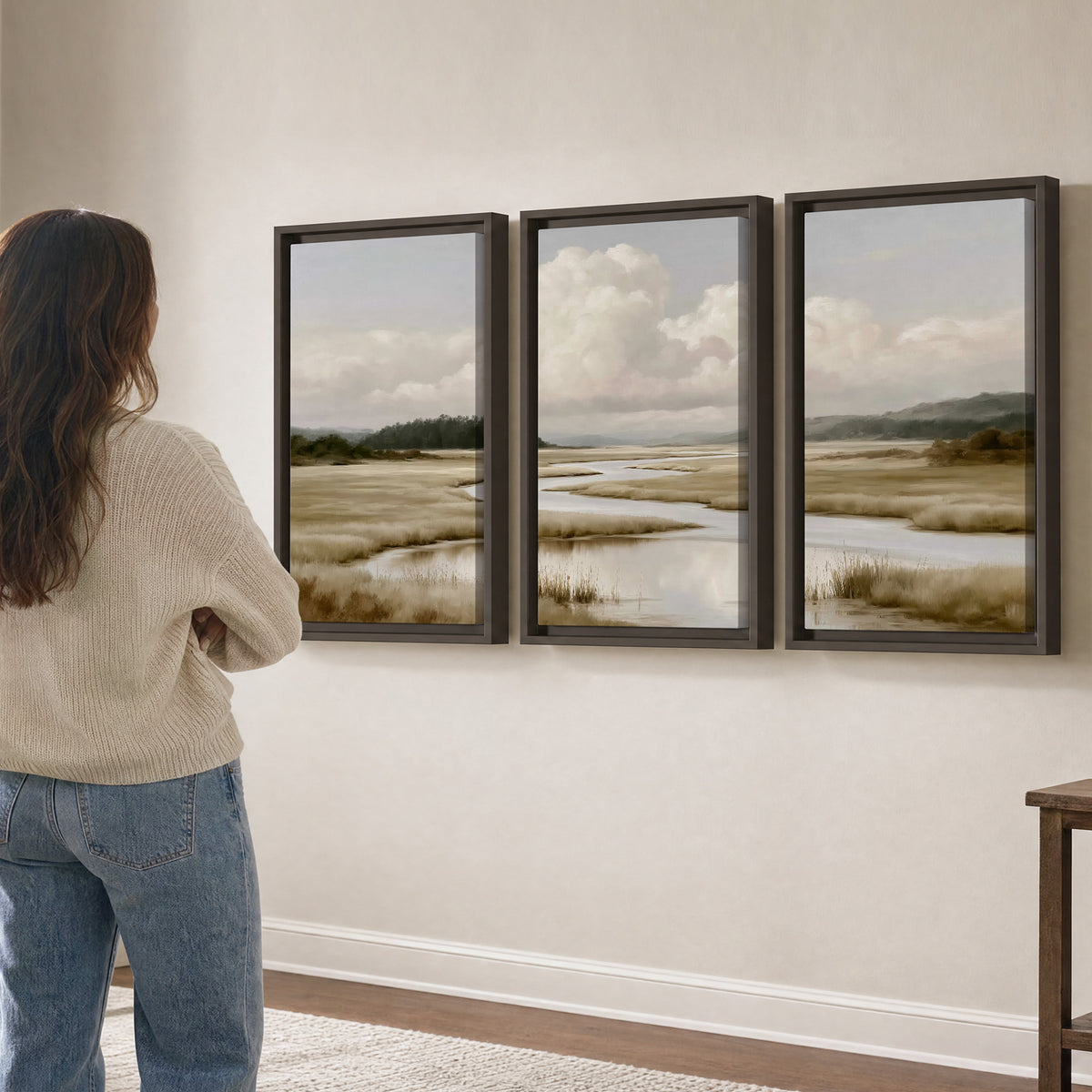 A pale winding waterway crossing quiet wetlands beneath billowing white clouds 3 piece framed canvas wall art three panel arrangement on a wall