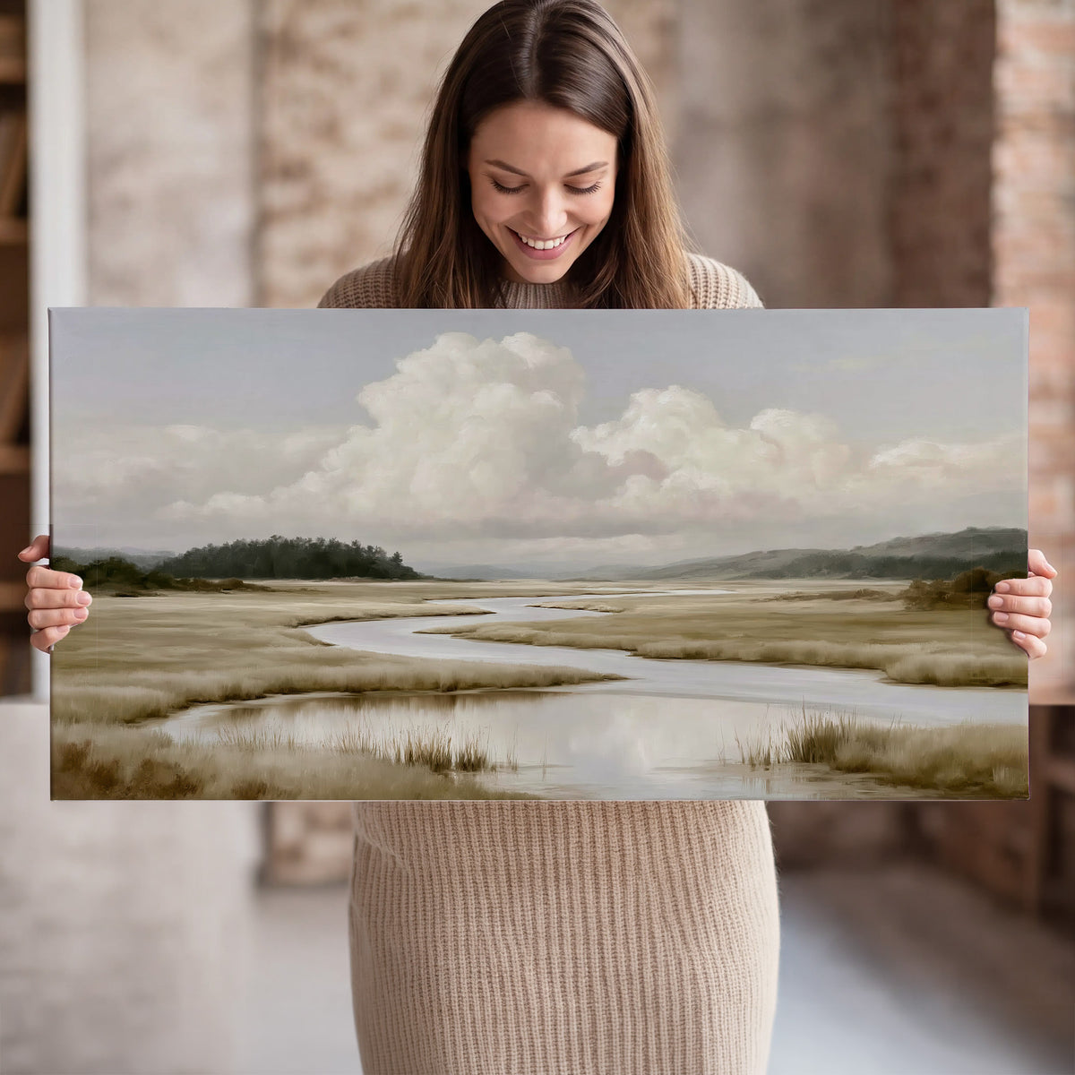 A pale winding waterway crossing quiet wetlands beneath billowing white clouds single canvas wall art held in hands