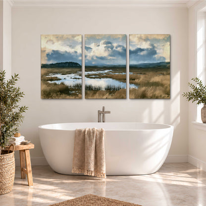 A wide open marsh with blue water and warm grasses beneath layered clouds 3 piece canvas wall art styled in an interior