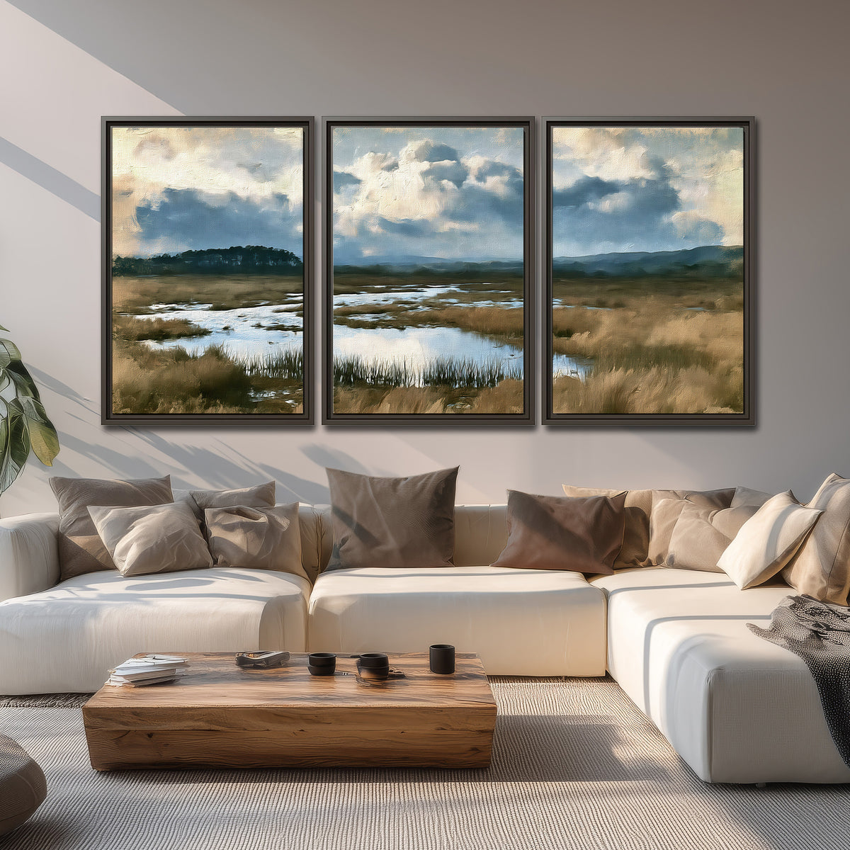 A wide open marsh with blue water and warm grasses beneath layered clouds 3 piece framed canvas wall art displayed in a living room