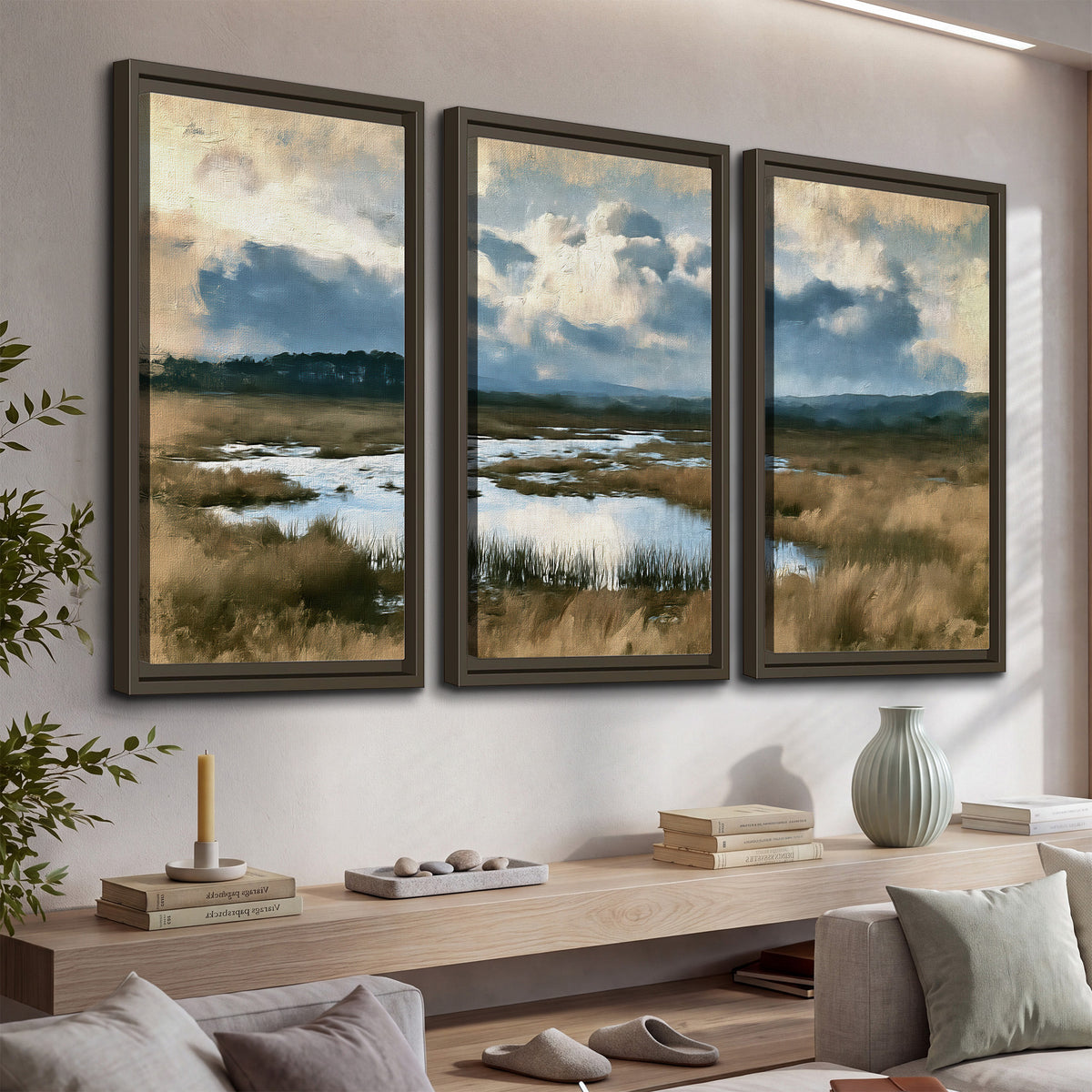 A wide open marsh with blue water and warm grasses beneath layered clouds 3 piece framed canvas wall art displayed in a console
