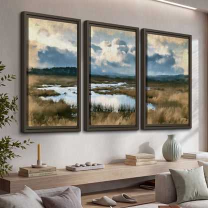 A wide open marsh with blue water and warm grasses beneath layered clouds 3 piece framed canvas wall art displayed in a console