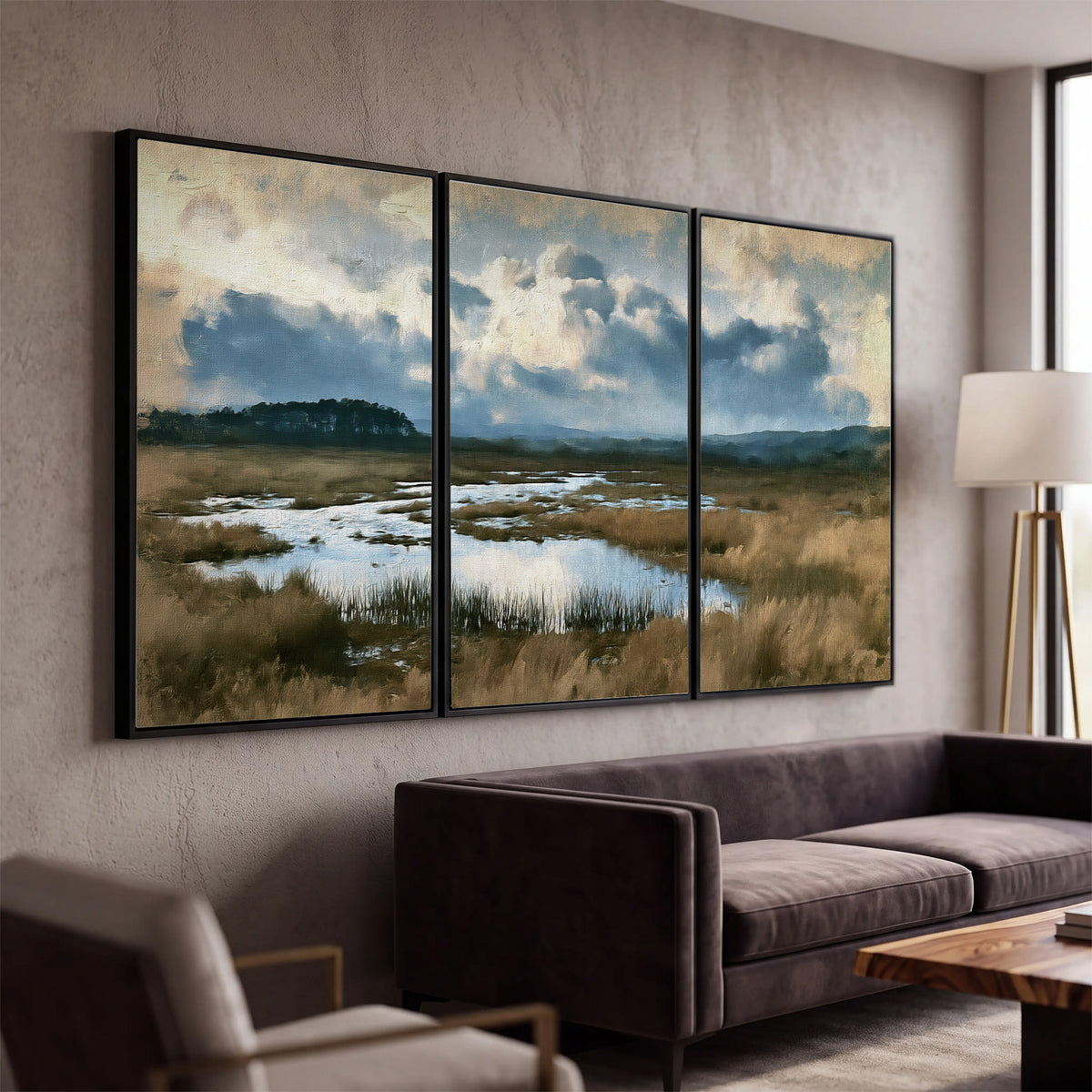 A wide open marsh with blue water and warm grasses beneath layered clouds 3 piece framed canvas wall art displayed in a modern living room