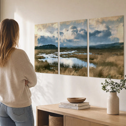 A wide open marsh with blue water and warm grasses beneath layered clouds set of 3 poster prints three panel arrangement on a wall