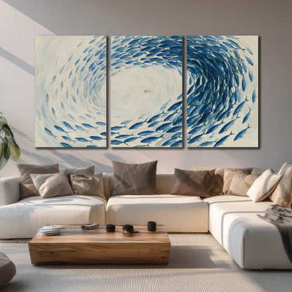 A circular school of blue fish flowing around a pale open center 3 piece canvas wall art displayed in a living room