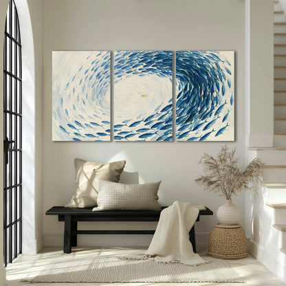 A circular school of blue fish flowing around a pale open center 3 piece canvas wall art displayed in a entryway