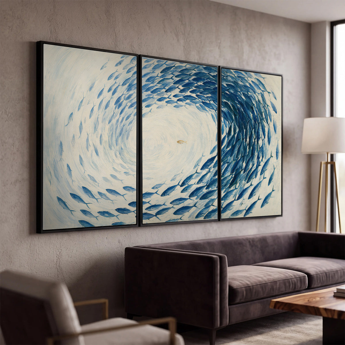 A circular school of blue fish flowing around a pale open center 3 piece framed canvas wall art displayed in a modern living room