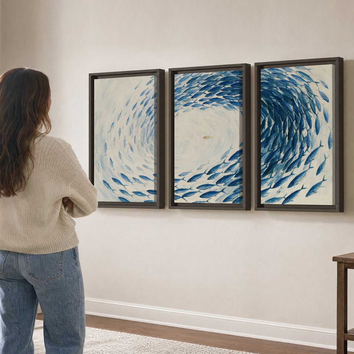A circular school of blue fish flowing around a pale open center 3 piece framed canvas wall art three panel arrangement on a wall