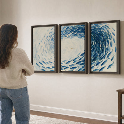 A circular school of blue fish flowing around a pale open center 3 piece framed canvas wall art three panel arrangement on a wall