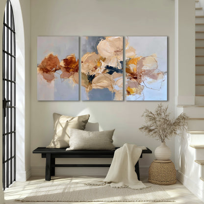 Loose ivory and ochre flower forms layered over a pale blue painterly background 3 piece canvas wall art displayed in a entryway