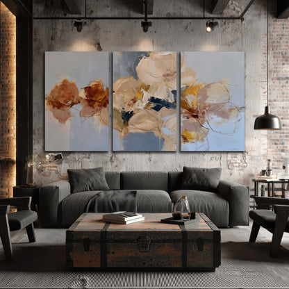 Loose ivory and ochre flower forms layered over a pale blue painterly background 3 piece canvas wall art displayed in a industrial room