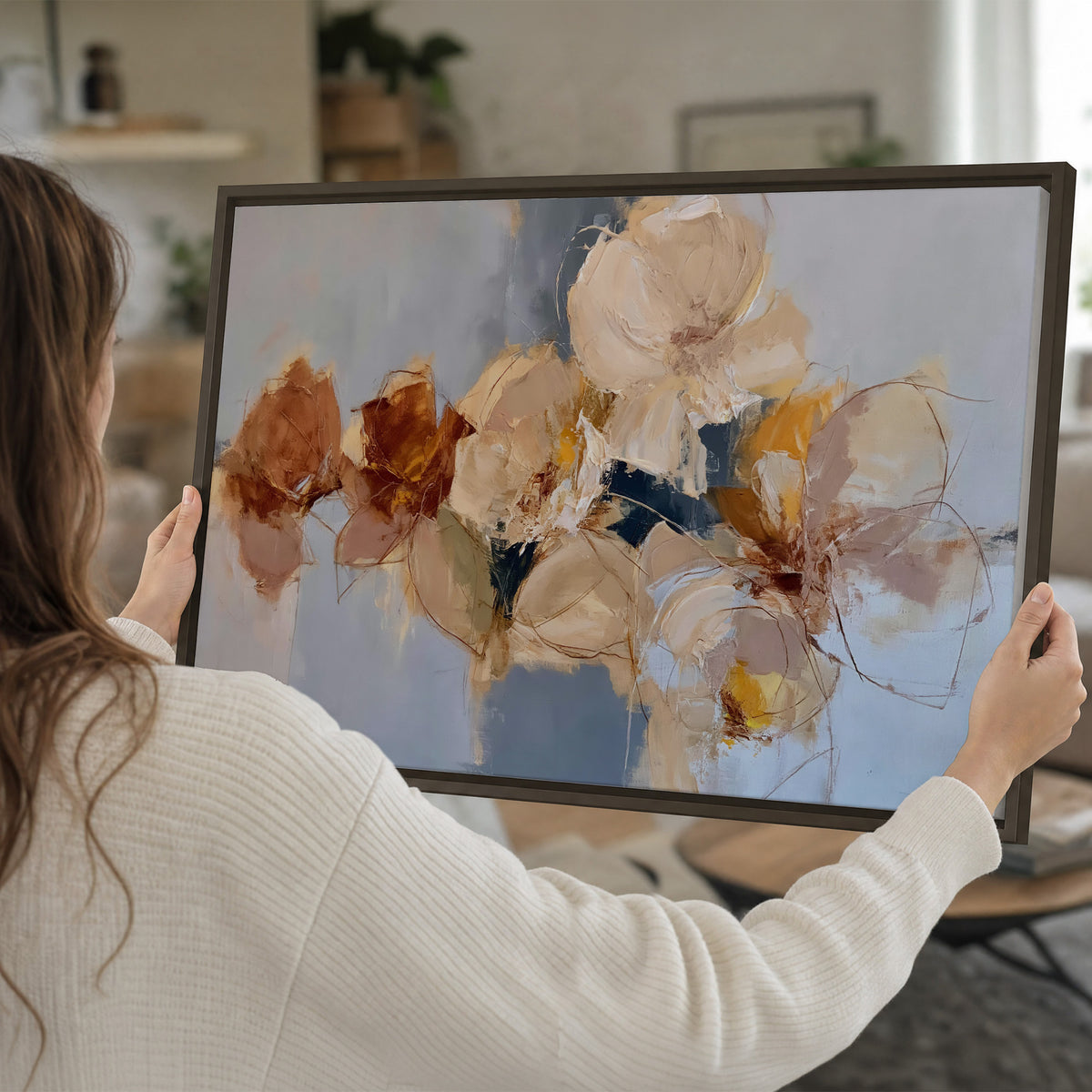Loose ivory and ochre flower forms layered over a pale blue painterly background single framed canvas wall art held in hands