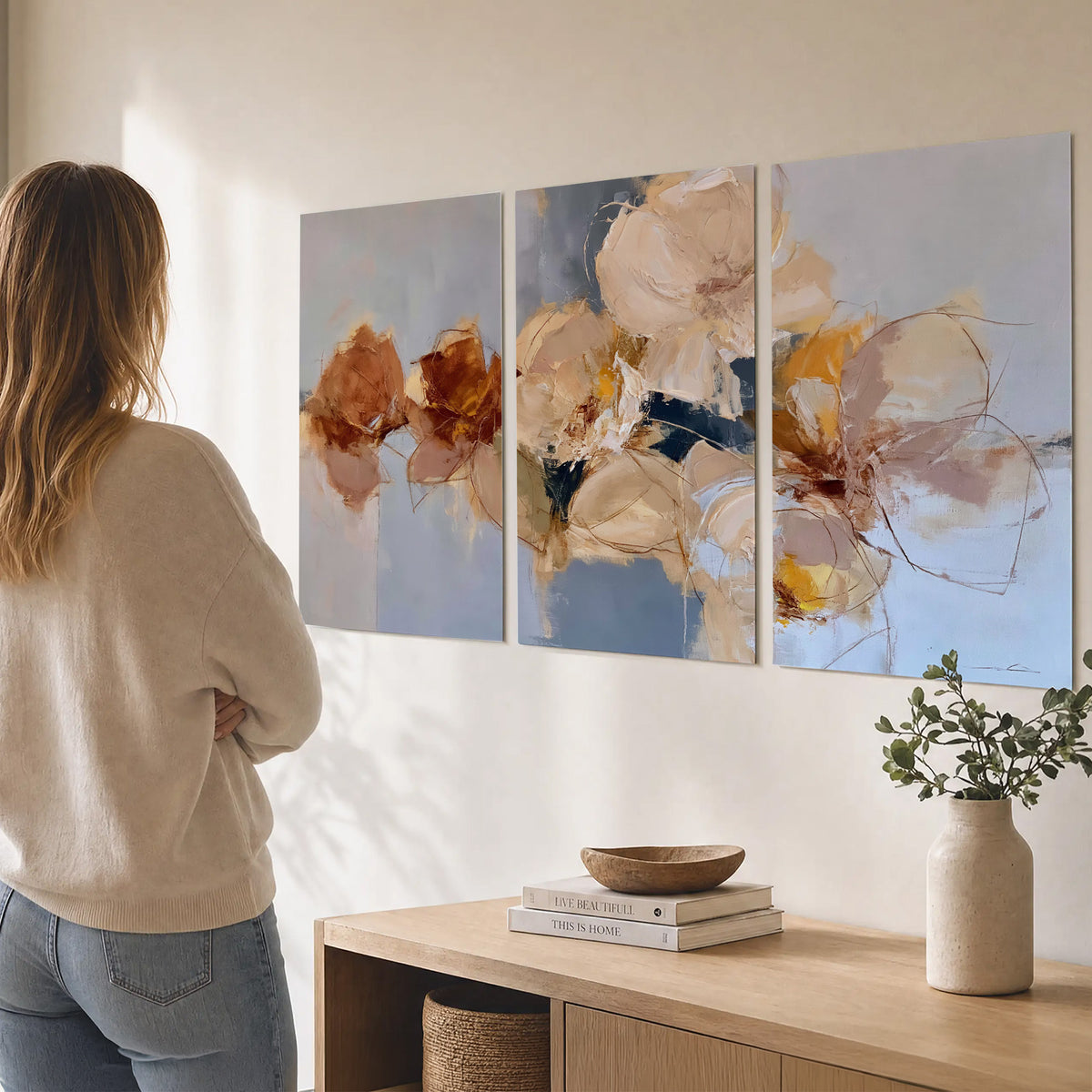 Loose ivory and ochre flower forms layered over a pale blue painterly background set of 3 poster prints three panel arrangement on a wall