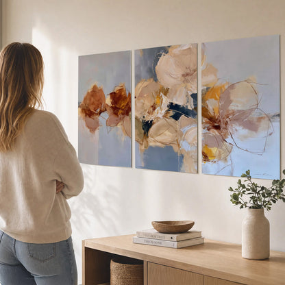 Loose ivory and ochre flower forms layered over a pale blue painterly background set of 3 poster prints three panel arrangement on a wall