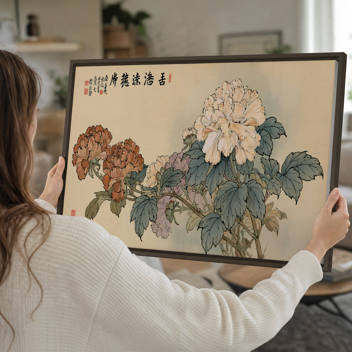 Pale pink peonies and green leaves on a warm beige background with decorative script single framed canvas wall art held in hands