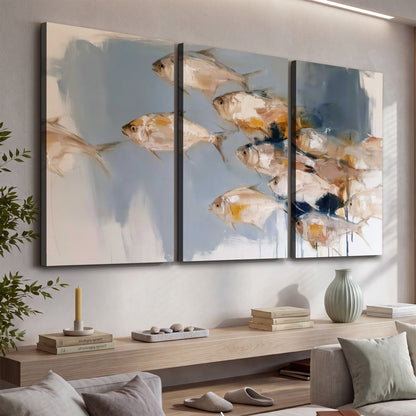 Small blue and golden fish moving across a pale layered abstract background 3 piece canvas wall art displayed in a console