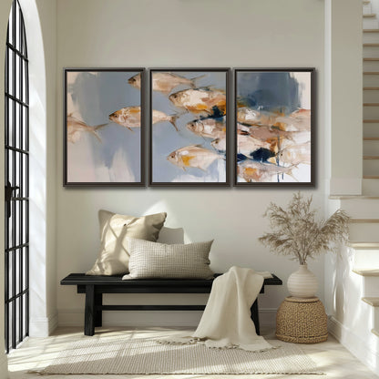 Small blue and golden fish moving across a pale layered abstract background 3 piece framed canvas wall art displayed in a entryway