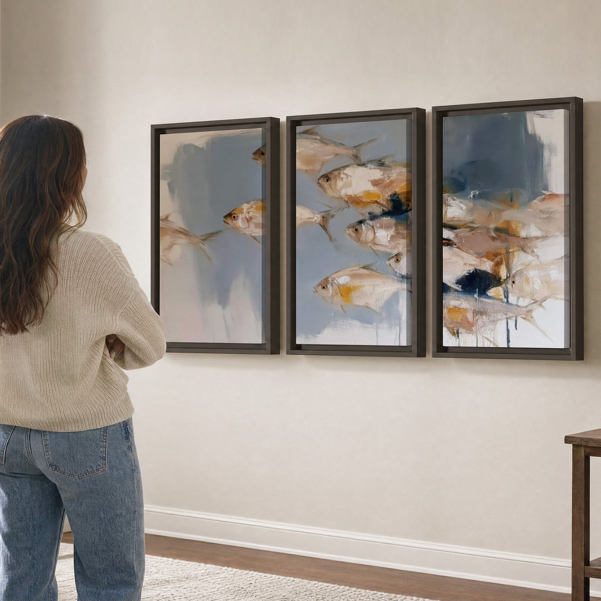 Small blue and golden fish moving across a pale layered abstract background 3 piece framed canvas wall art three panel arrangement on a wall