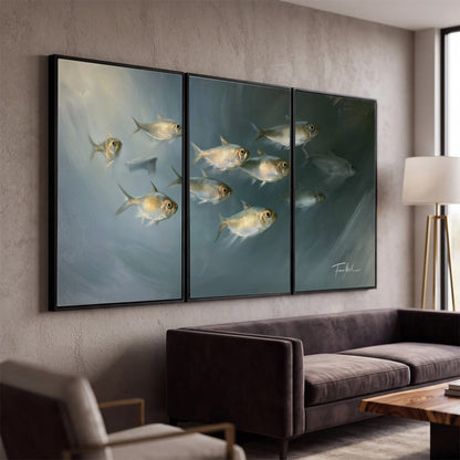 A small school of pale golden fish swimming across dark blue-green water 3 piece framed canvas wall art displayed in a modern living room