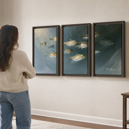 A small school of pale golden fish swimming across dark blue-green water 3 piece framed canvas wall art three panel arrangement on a wall
