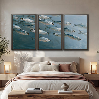 A school of silver fish moving together through cool blue water 3 piece framed canvas wall art displayed in a bedroom