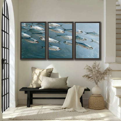 A school of silver fish moving together through cool blue water 3 piece framed canvas wall art displayed in a entryway