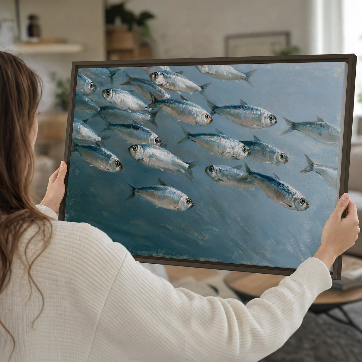 A school of silver fish moving together through cool blue water single framed canvas wall art held in hands
