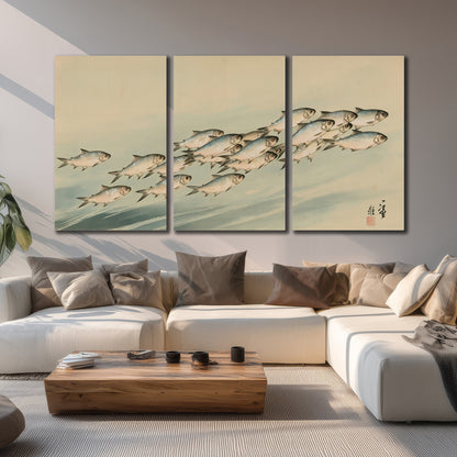 A flowing school of small fish above pale blue water on a cream ground 3 piece canvas wall art displayed in a living room