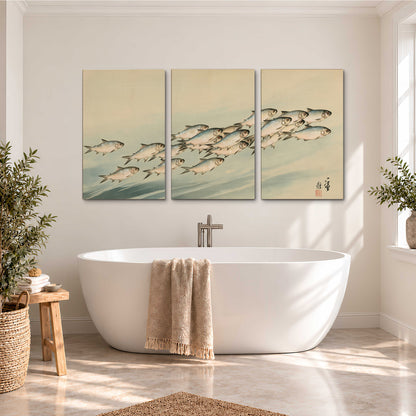 A flowing school of small fish above pale blue water on a cream ground 3 piece canvas wall art styled in an interior