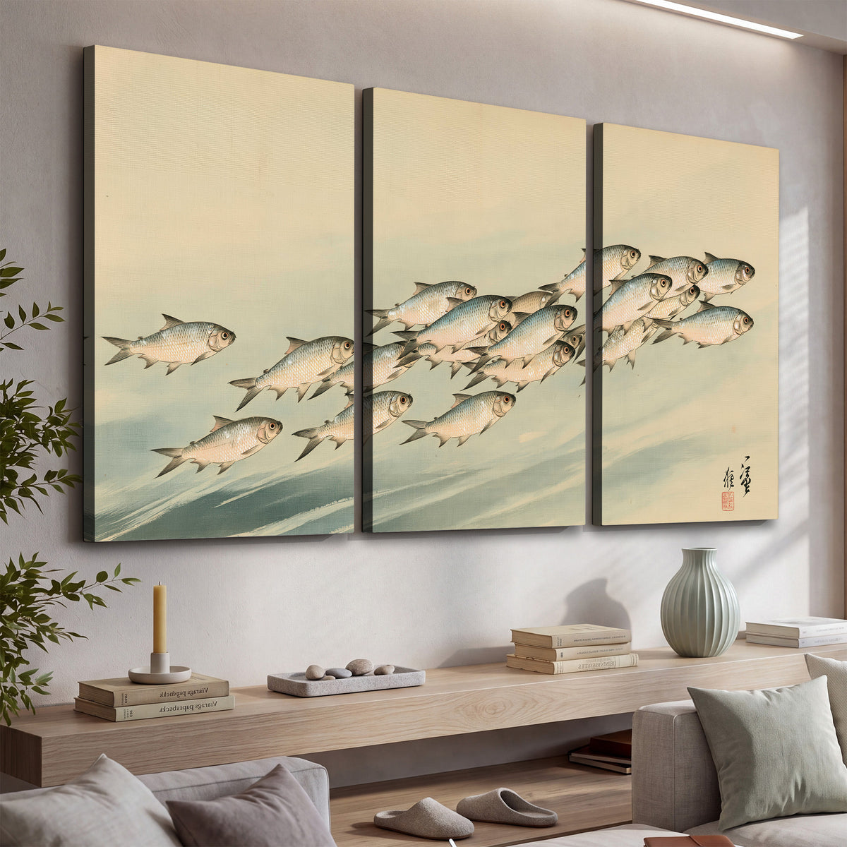 A flowing school of small fish above pale blue water on a cream ground 3 piece canvas wall art displayed in a console