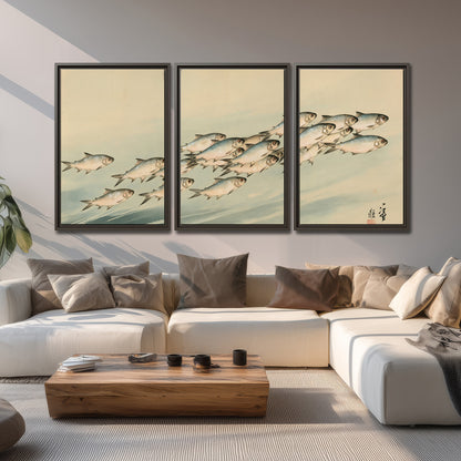 A flowing school of small fish above pale blue water on a cream ground 3 piece framed canvas wall art displayed in a living room