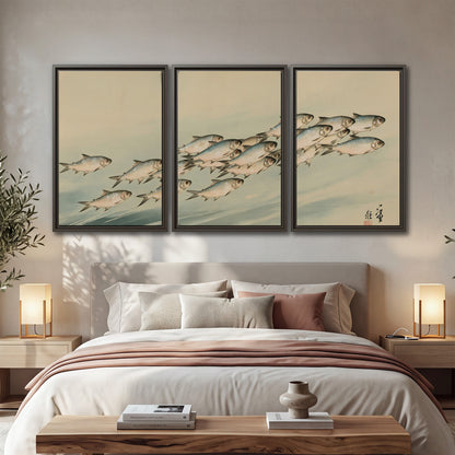 A flowing school of small fish above pale blue water on a cream ground 3 piece framed canvas wall art displayed in a bedroom