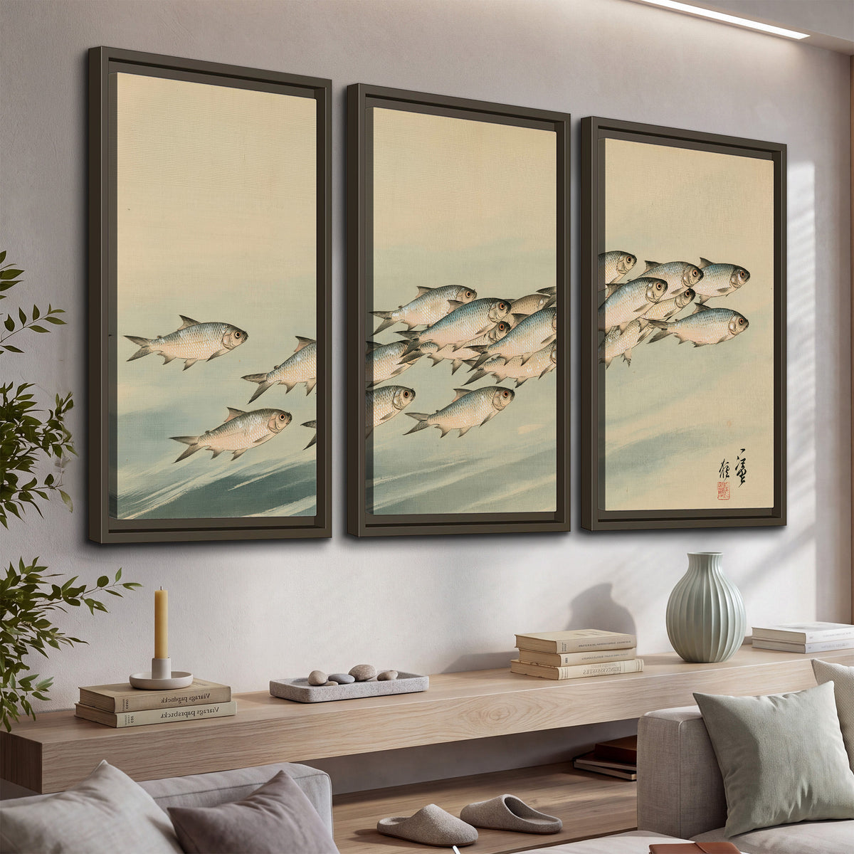 A flowing school of small fish above pale blue water on a cream ground 3 piece framed canvas wall art displayed in a console
