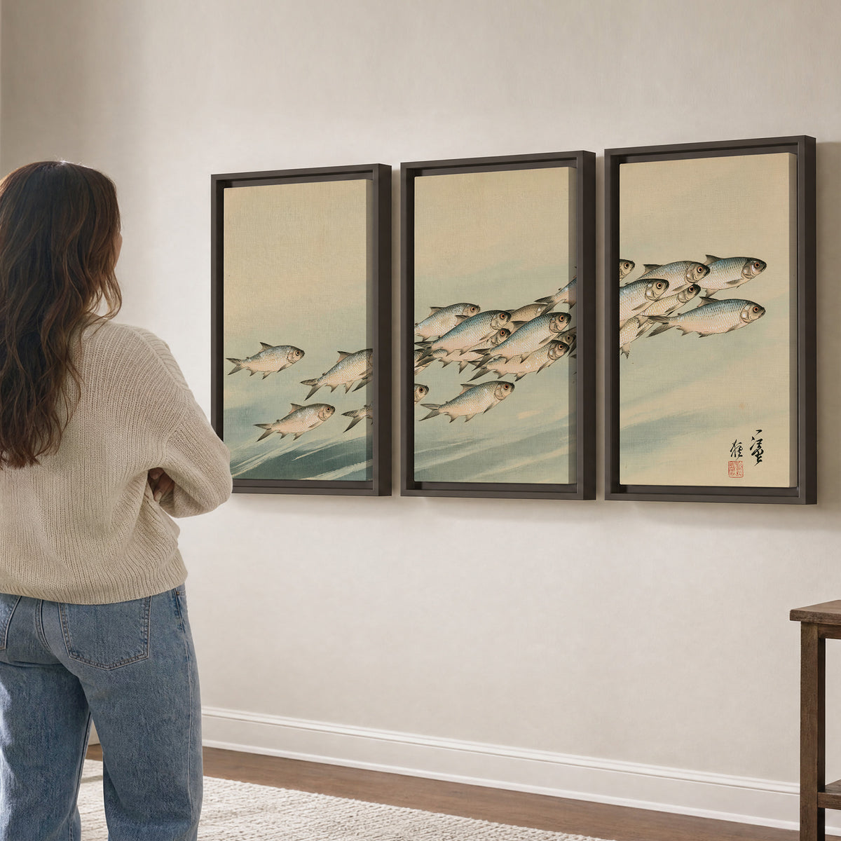 A flowing school of small fish above pale blue water on a cream ground 3 piece framed canvas wall art three panel arrangement on a wall