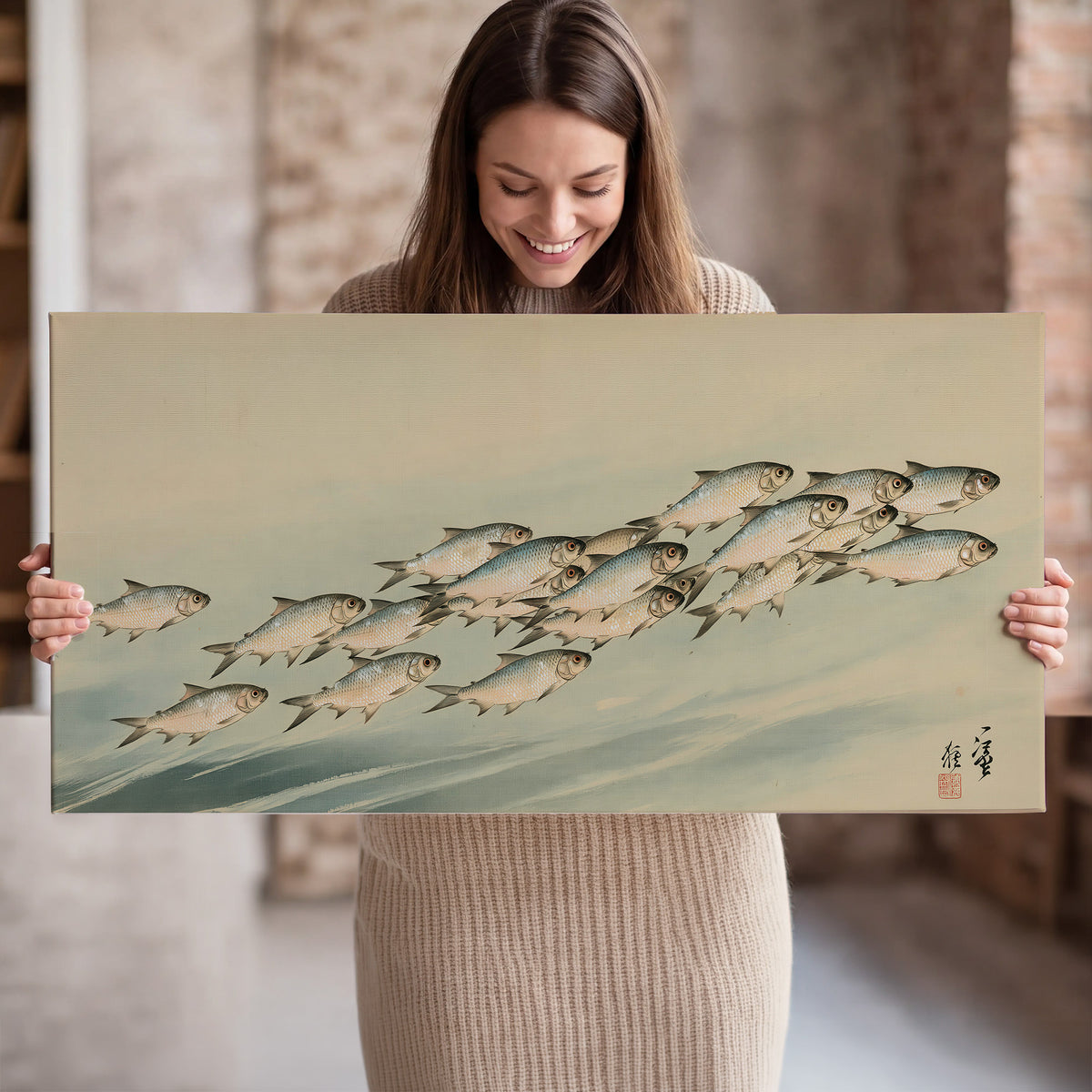 A flowing school of small fish above pale blue water on a cream ground single canvas wall art held in hands