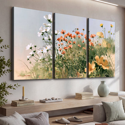 White and orange meadow flowers with fine green stems under a pale sky 3 piece canvas wall art displayed in a console