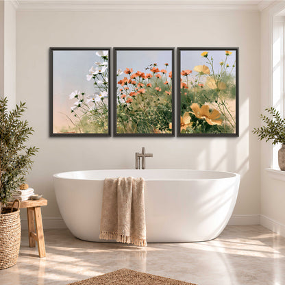 White and orange meadow flowers with fine green stems under a pale sky 3 piece framed canvas wall art styled in an interior