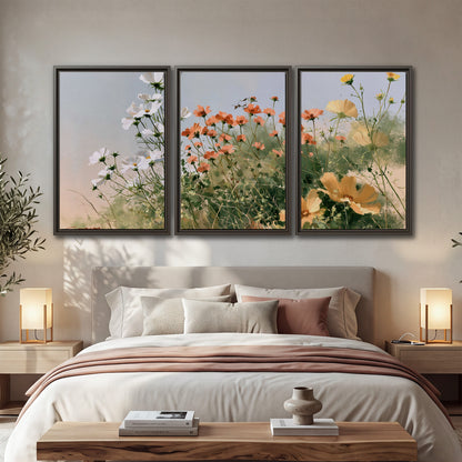 White and orange meadow flowers with fine green stems under a pale sky 3 piece framed canvas wall art displayed in a bedroom