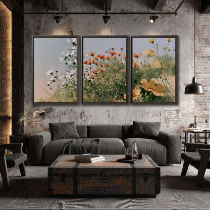 White and orange meadow flowers with fine green stems under a pale sky 3 piece framed canvas wall art displayed in a industrial room
