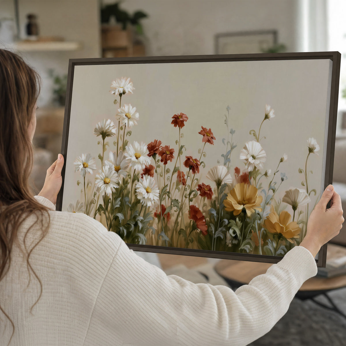 White wildflowers and warm red blossoms rising against a soft beige background single framed canvas wall art held in hands